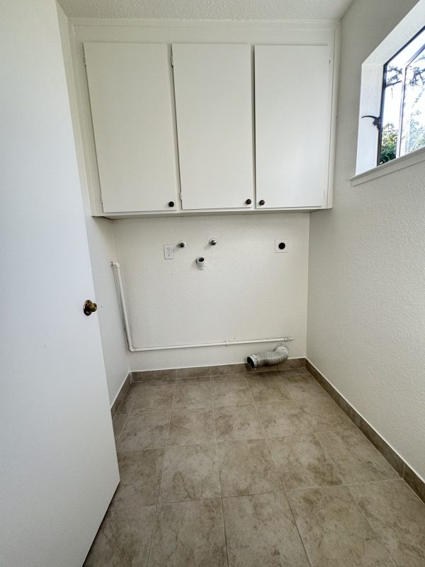 A white kitchen interior with cabinetry and a tiled floor, highlighting a fresh and inviting cooking space