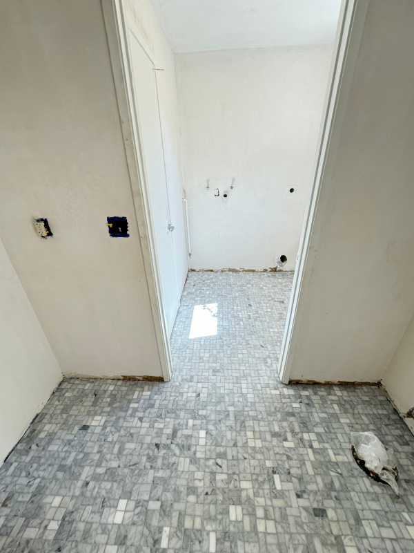Clean modern bathroom with ceramic tile floor and closed white door
